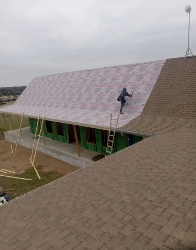 Worker preparing underlayment for a metal roof installation in Demopolis